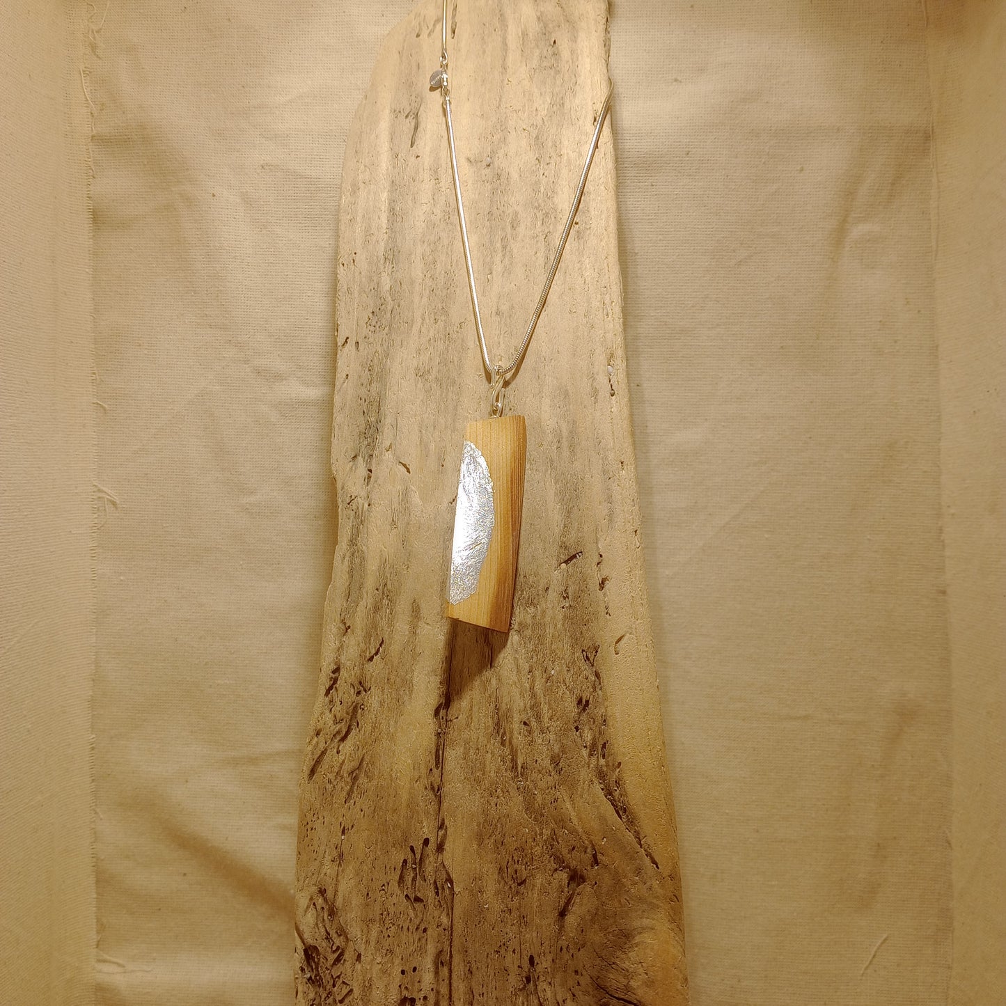 The Twist steam bent yew pendant with silver leaf on sterling silver snake chain